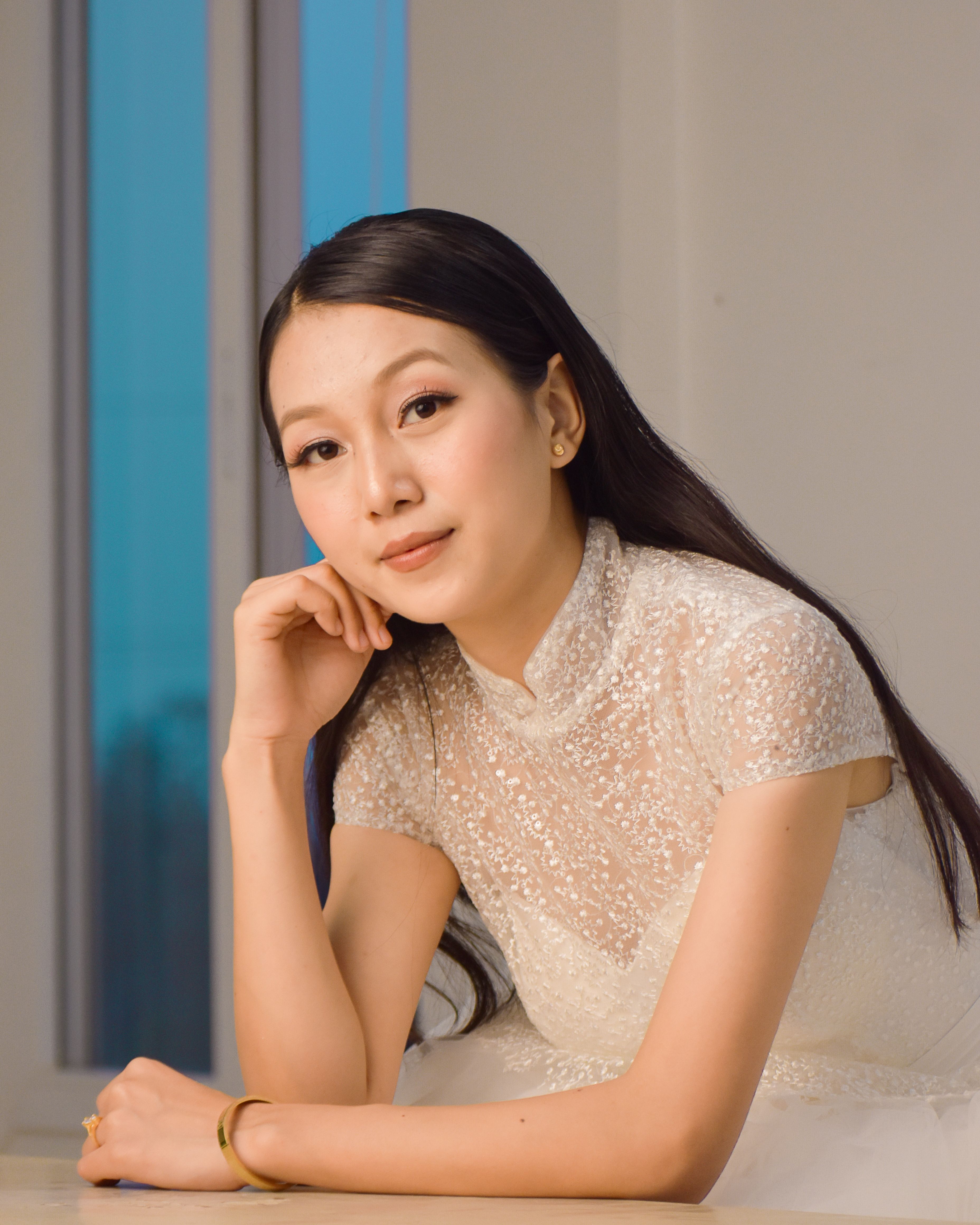 Stunning portrait of an elegant South Asian woman in a white dress, striking a thoughtful pose indoors.
