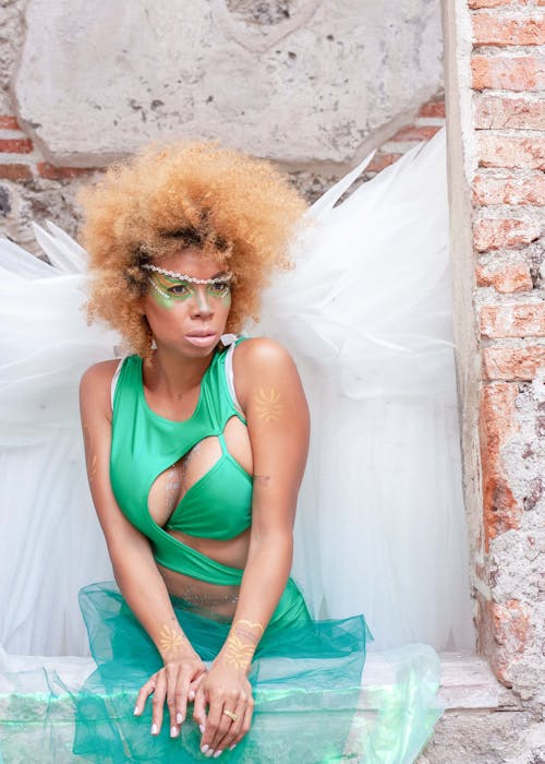 A woman with an afro wearing a green dress and wings