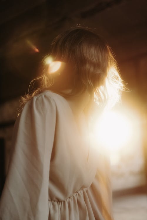 A woman in a white dress is looking at the sun