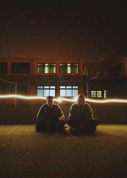 夜色中，两个人坐在屋外，被明亮的光线照亮