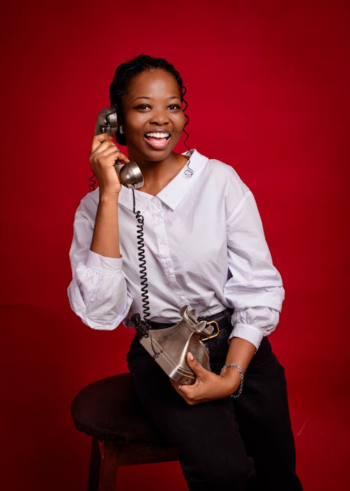 A smiling woman holding a phone and talking on it