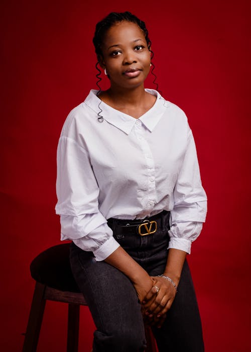 A woman in a white shirt and black pants sitting on a stool