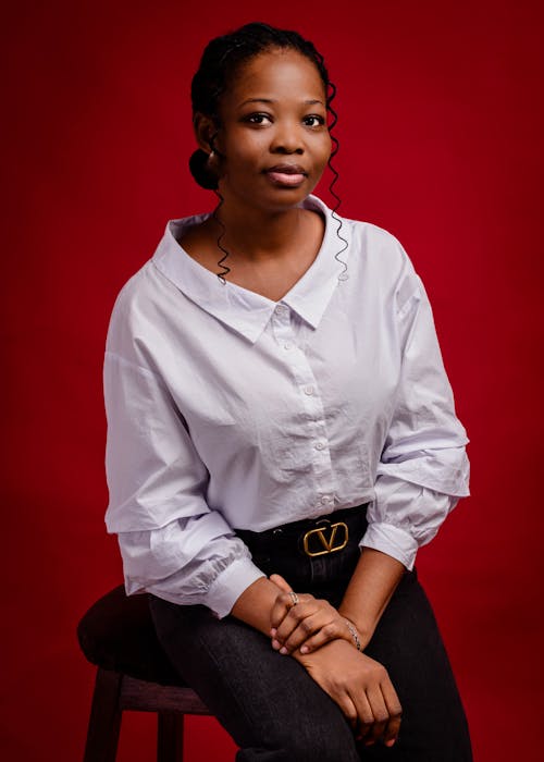 A woman in a white shirt and black pants sitting on a stool