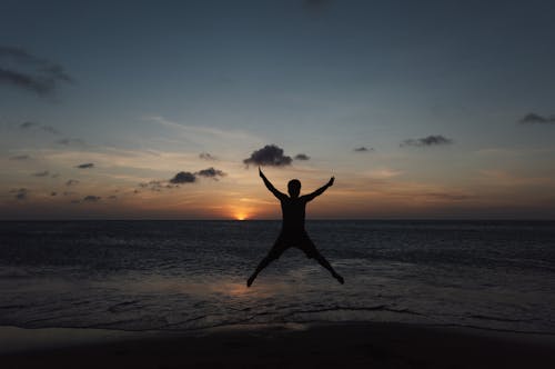 Silhouette of a Person Jumping on a Beach at Sunset