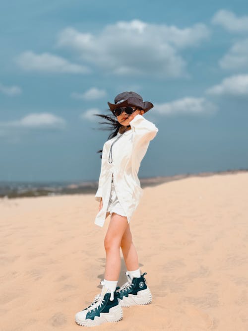 A woman in a hat and white shoes on the beach