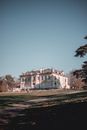 Picturesque view of beautiful majestic two storey mansion surrounded by park in countryside on clear day