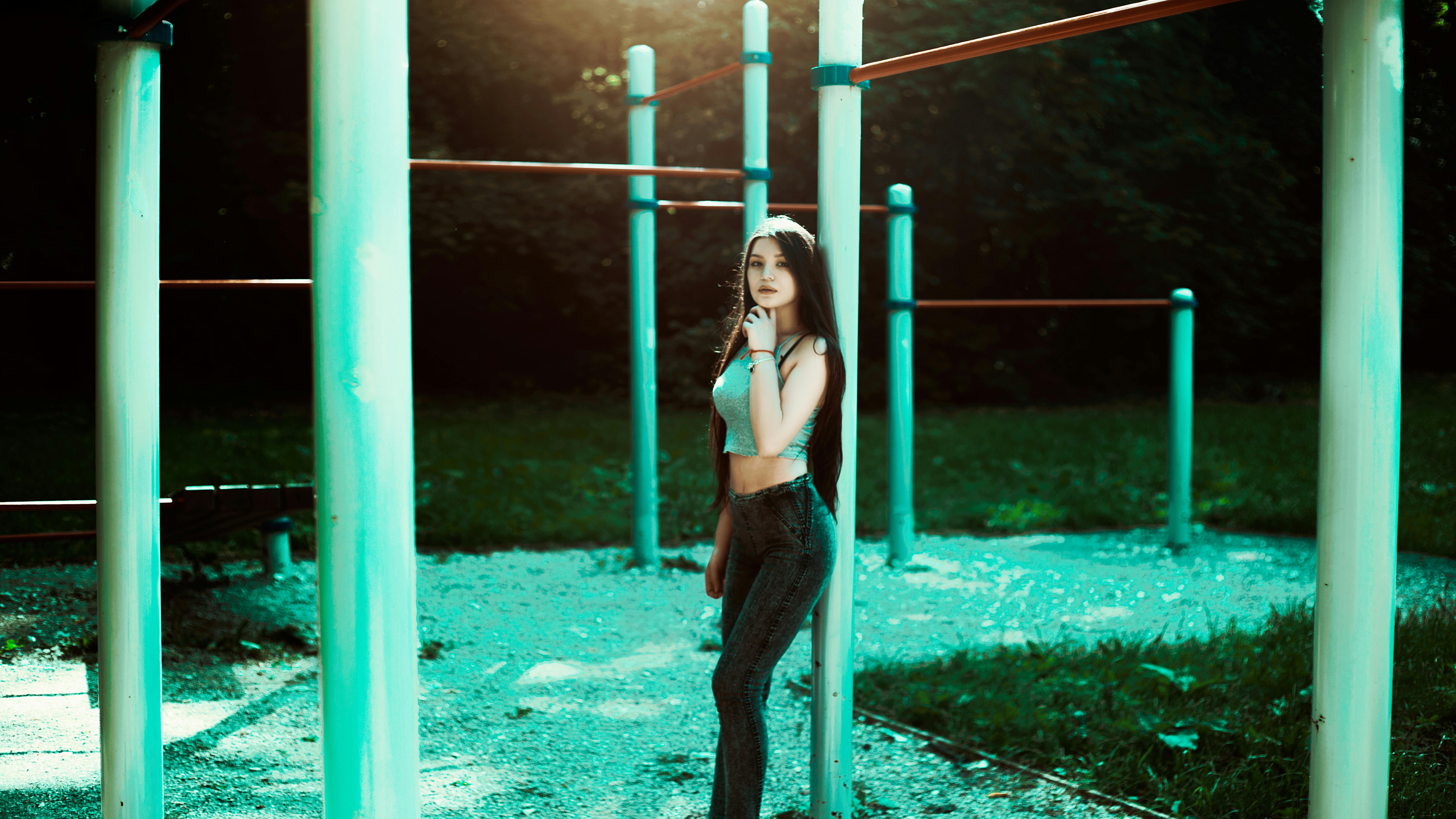 免费 女人靠在绿色的金属杆，抱着她的下巴用她的左手 素材图片