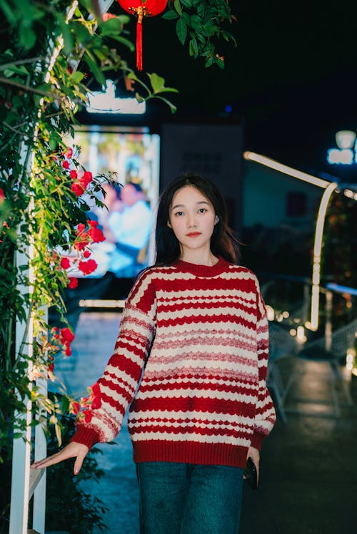 A woman in a red and white sweater standing in front of a christmas tree