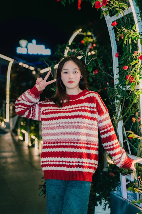 A woman in a red and white sweater is posing for a photo