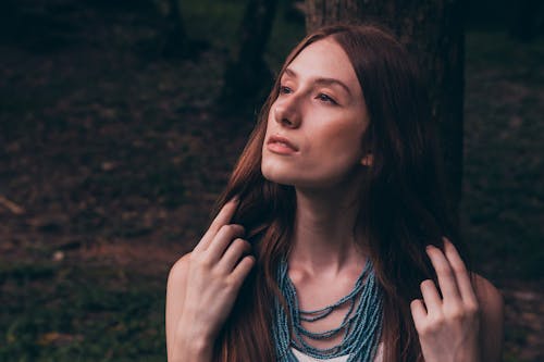 Photo of Woman Looking Away While Touching Her Hair
