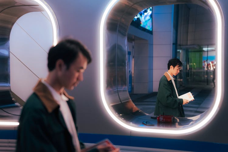 Reflection Of Man In Jacket With Book In Mirror