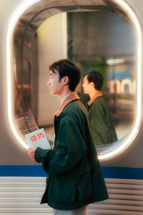 A man standing in front of a train with a book