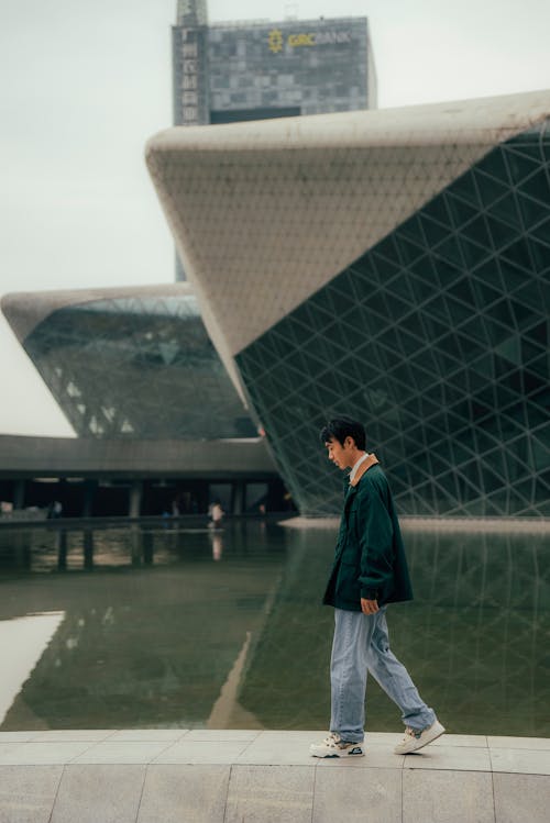 A man walking in front of a building with a large glass roof