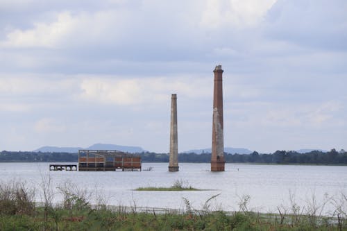 Two chimneys are sitting in the water near a body of water