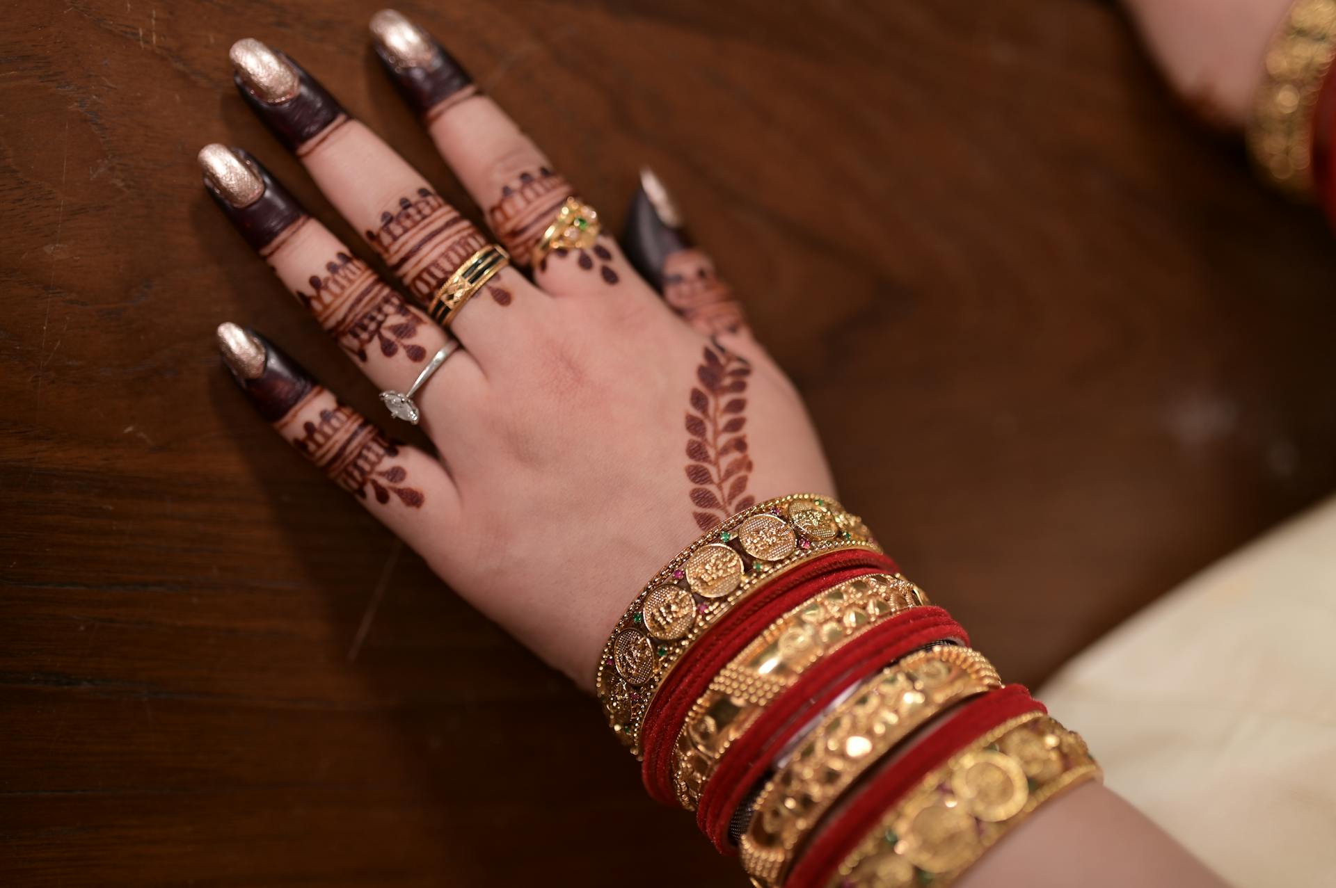 Hand adorned with intricate mehendi and gold jewelry showcasing traditional Indian culture.