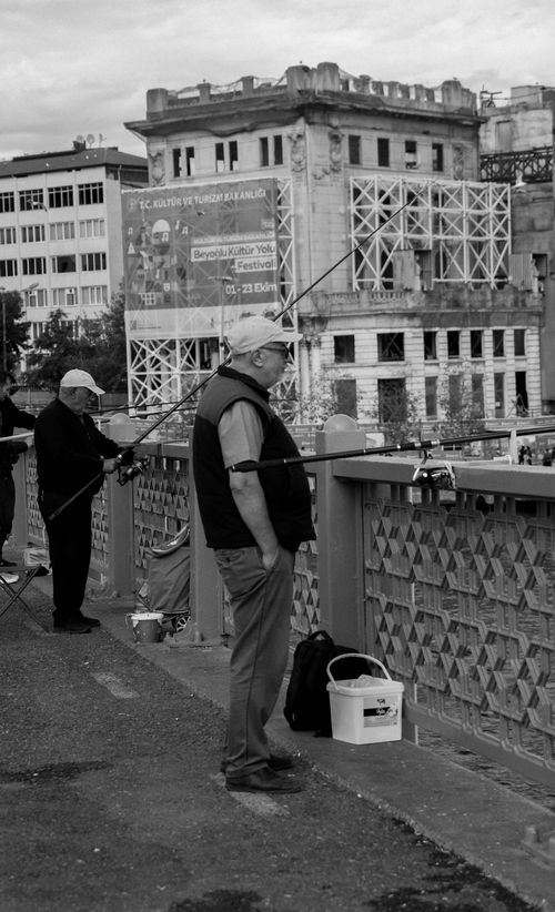 Free Black and white photo of elderly men fishing on a historic Istanbul bridge. Stock Photo