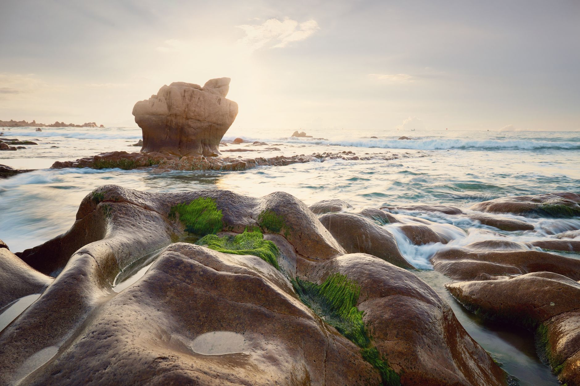 Stunning moss-covered rocks at sunrise on Bình Thuận's Co Thach Beach, Vietnam.