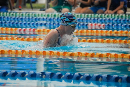 Swimmer in action during a competitive outdoor pool race, showcasing athletic skill and focus.