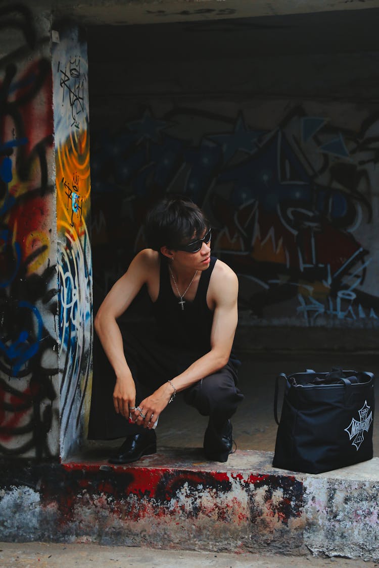 Young Man Squatting By A Graffiti Wall