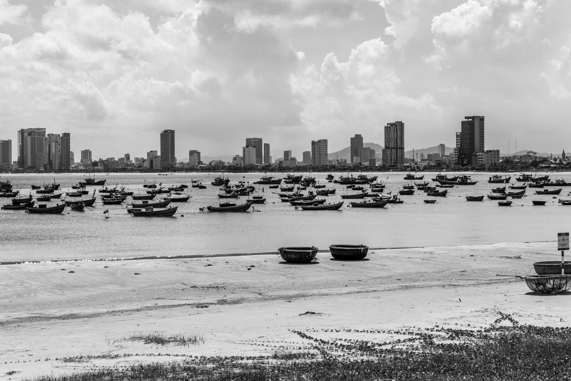 Black and white panorama of Da Nang skyline with boats on the waterfront, showing urban coastal contrast.