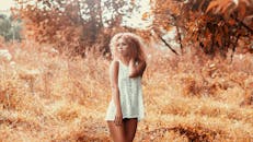 金色秋野中，一位卷发年轻女子的宁静肖像