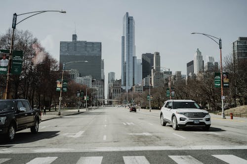 A car driving down a city street with tall buildings in the background