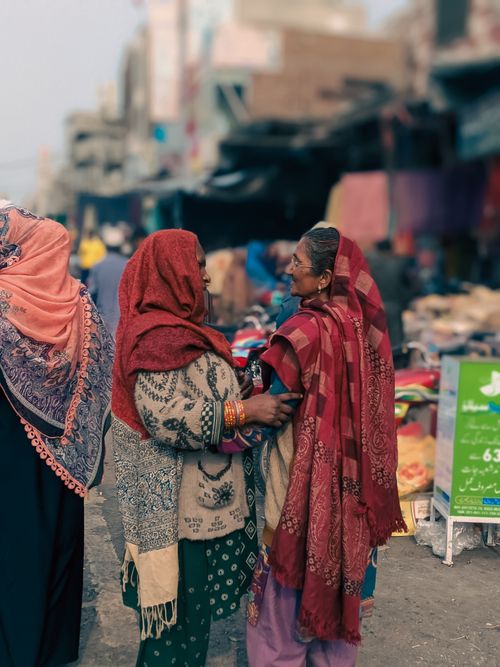 Free Two women in traditional attire share a conversation in the bustling streets of Faisalabad, Pakistan. Stock Photo