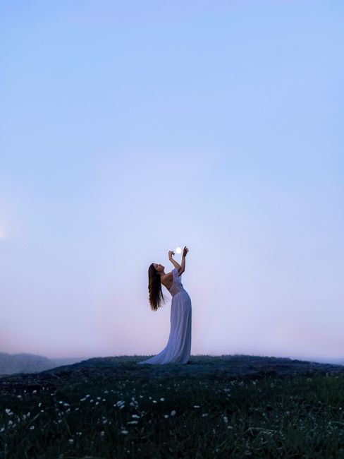 A serene image of an elegant woman in a flowing dress standing in a moonlit meadow.