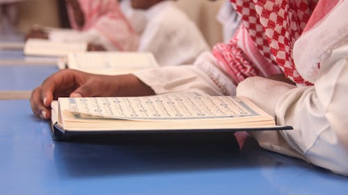 A man in a red and white scarf reading a book