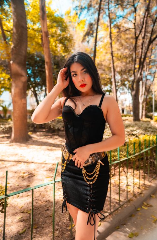 Free Elegant woman in a black dress poses confidently in a sunny park in Mexico City, embracing fall fashion trends. Stock Photo