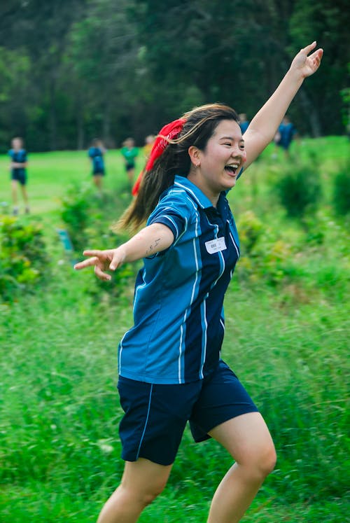 Shallow Focus Photo of Woman in Blue Polo Shirt Raising Left Hand