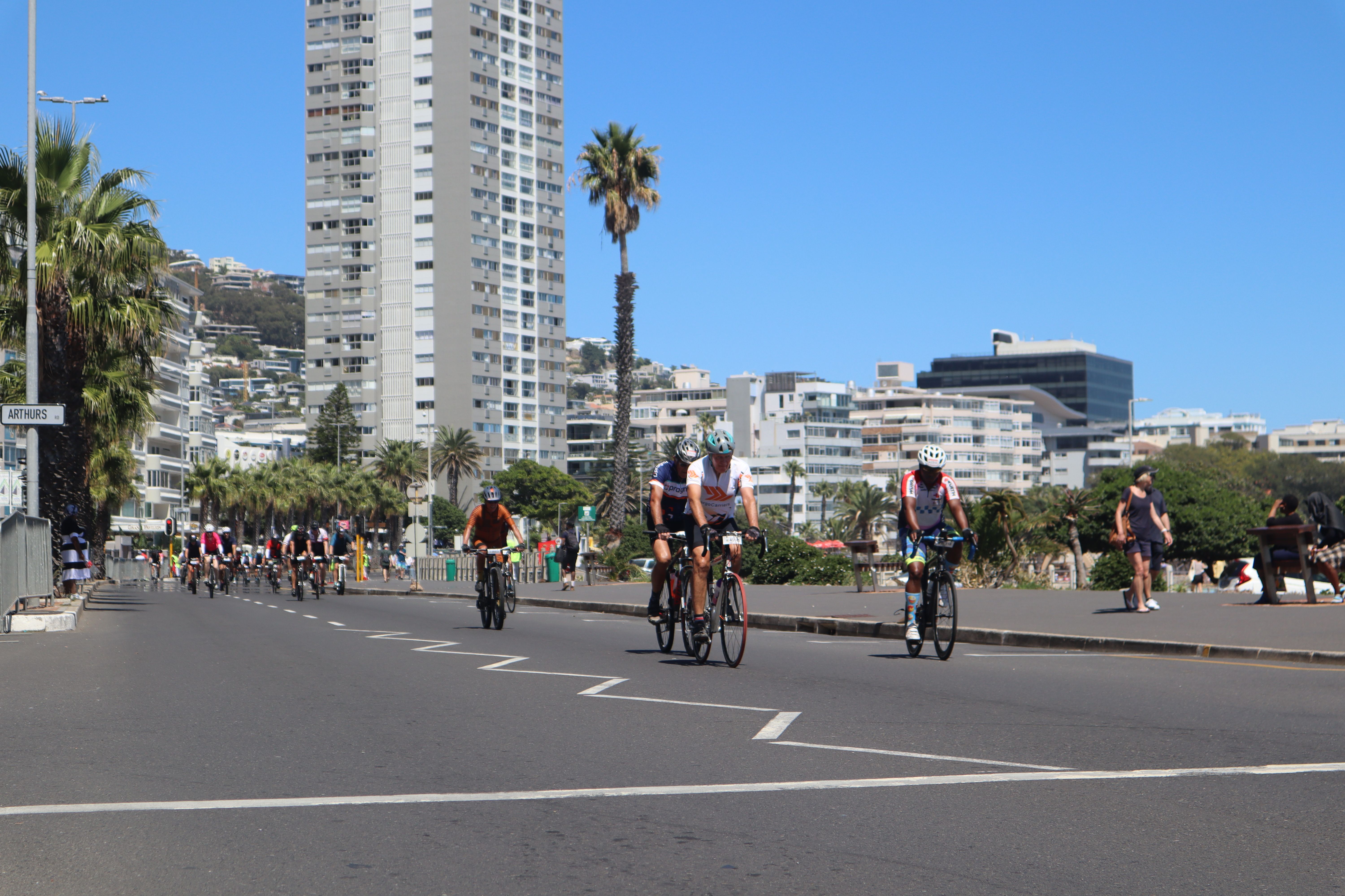 Cyclists participating in a race through Cape Town's urban landscape with clear blue skies.