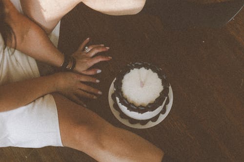 Leg and Hands of Woman Sitting with Birthday Cake on Floor