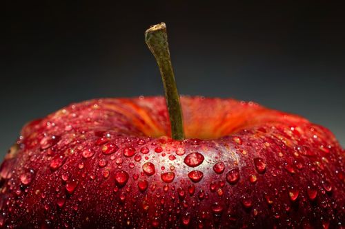 Free Vibrant close-up of a red apple covered in water droplets against a dark background. Stock Photo