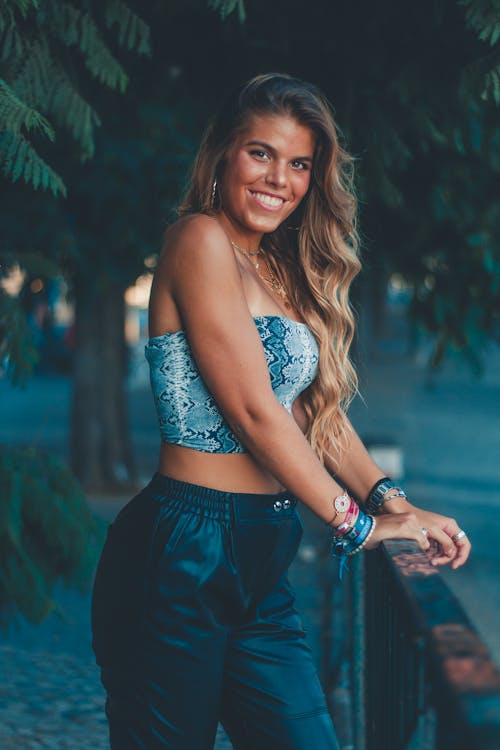 Woman Standing Beside Metal Fence Under Green Trees