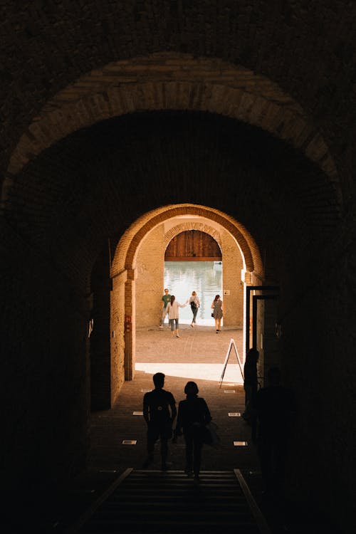 Two people walking through an archway in a tunnel