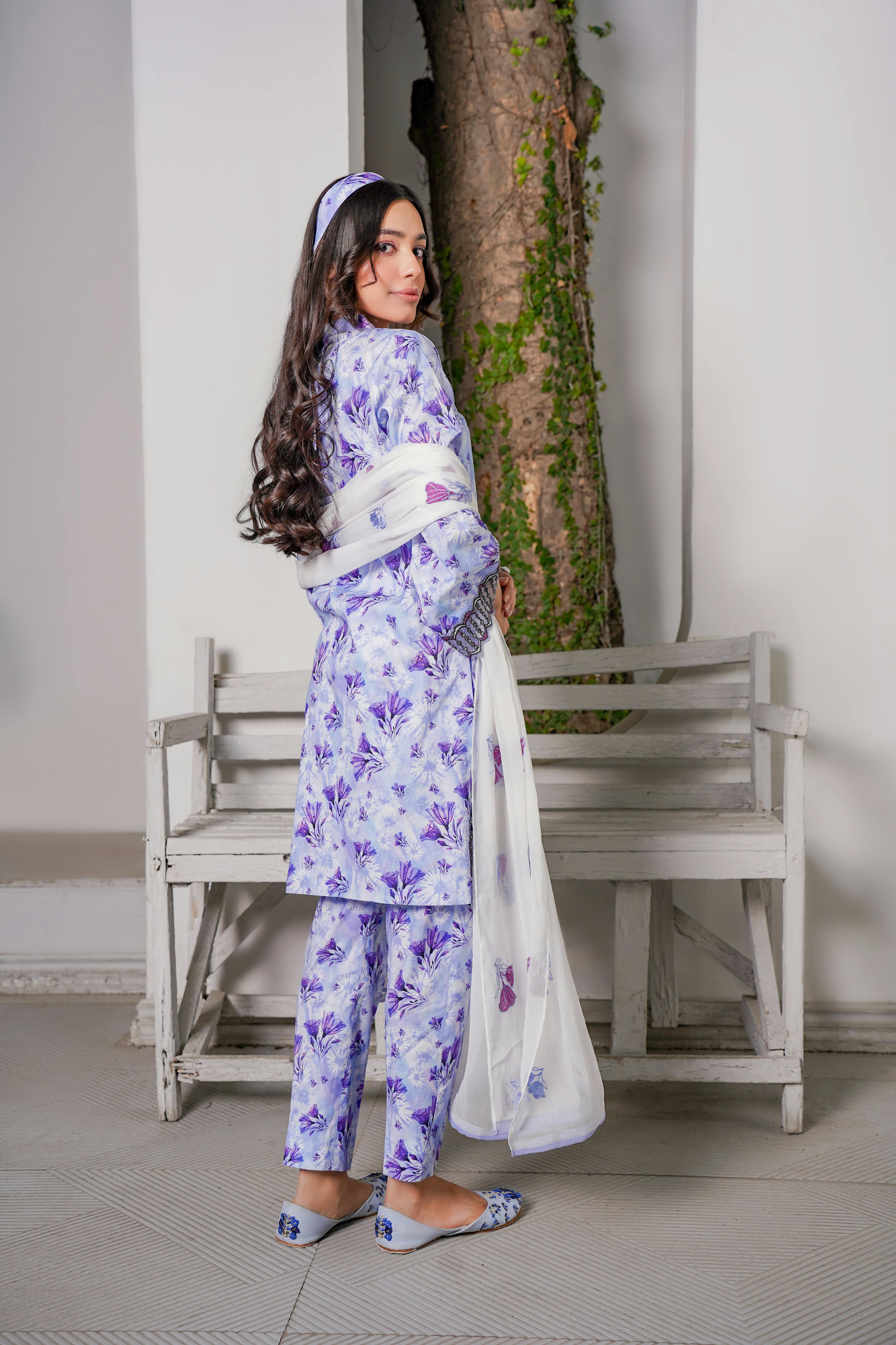 brunette woman in purple dress posing by white bench