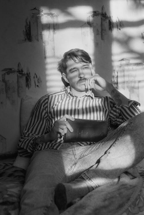 A man sitting on a bed smoking a cigarette