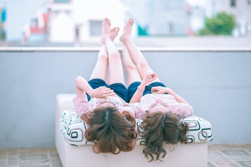Kostenlos Zwei Mädchen, Die Auf Sofa Liegen, Während Sie Nach Oben Schauen Stock-Foto