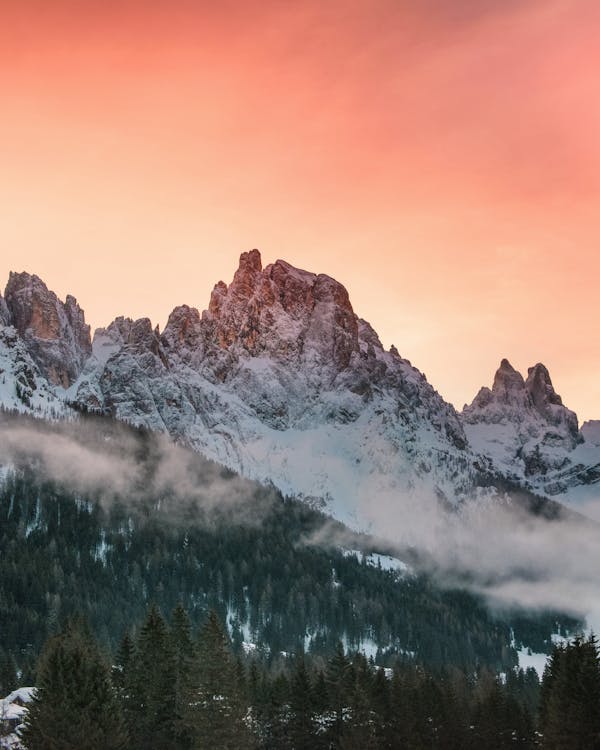 A sunset over the mountains with snow covered trees