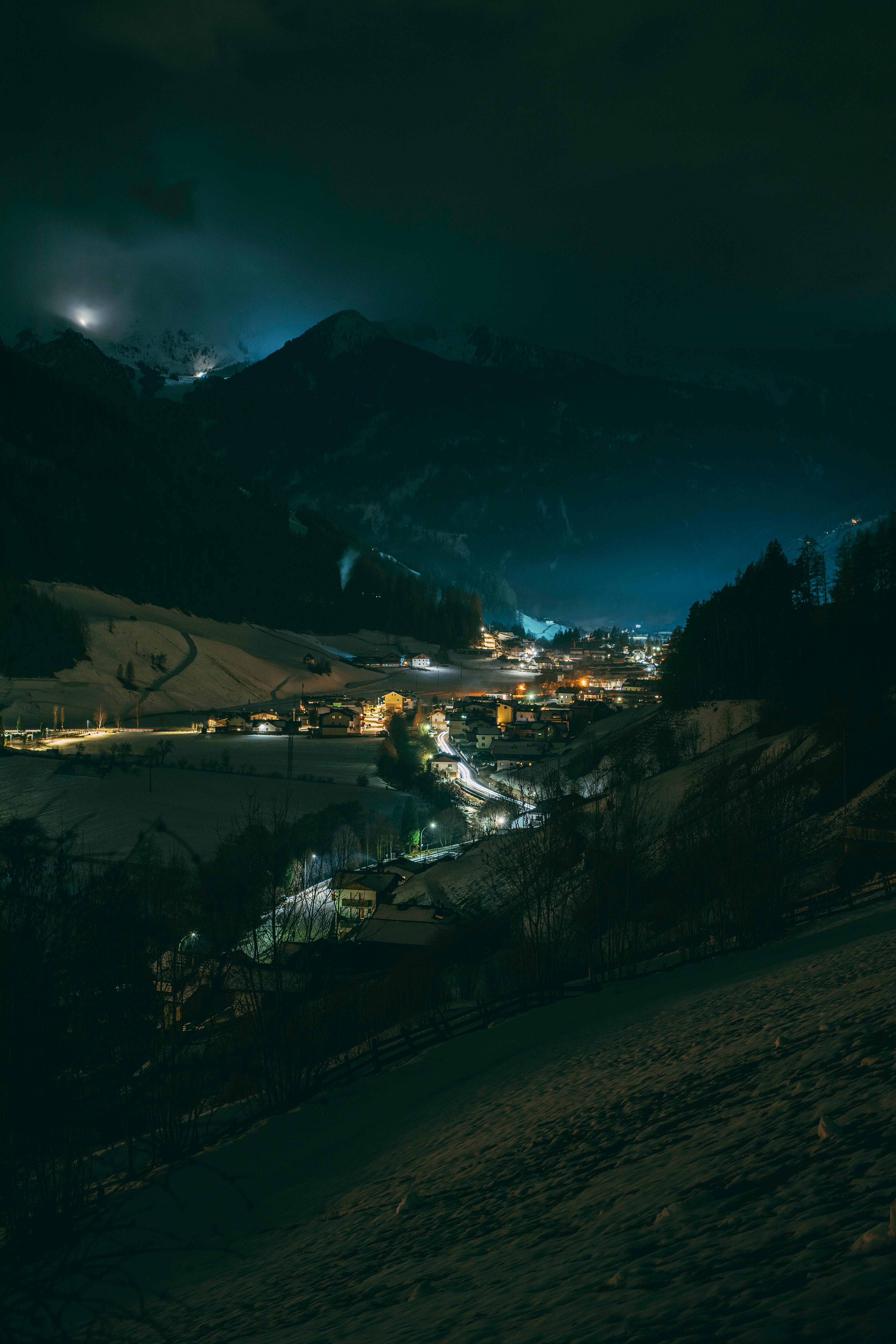 Peaceful alpine village illuminated at night with mountains in the background.