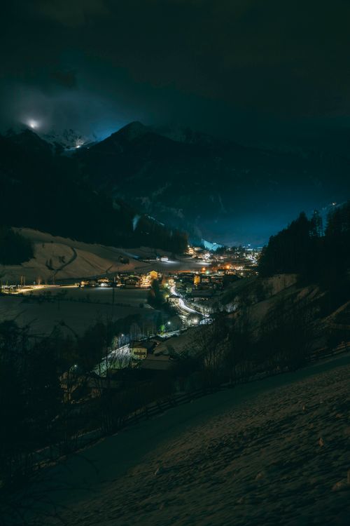 Free Peaceful alpine village illuminated at night with mountains in the background. Stock Photo