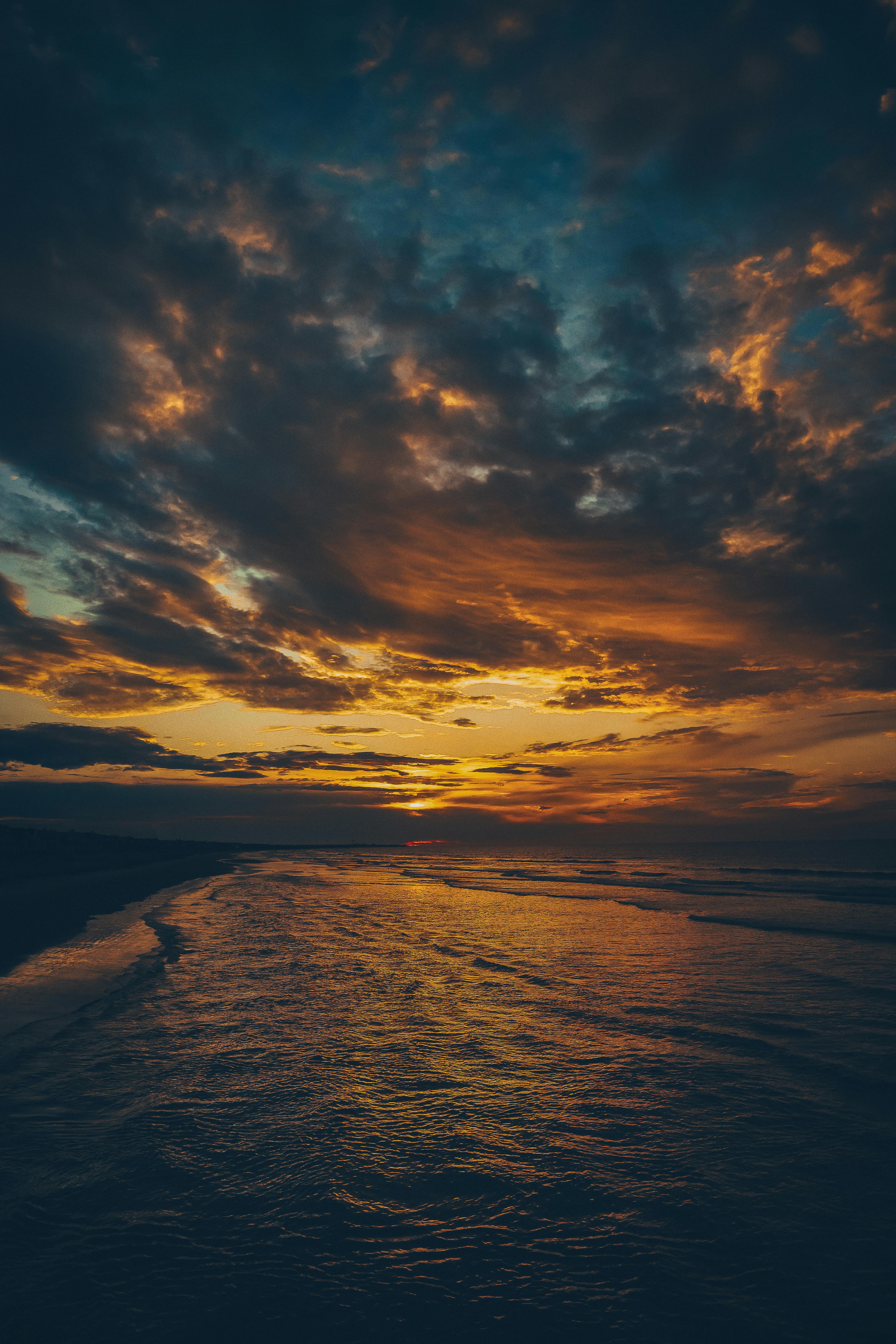 Stunning sunset over the ocean with vibrant colors and dramatic clouds reflecting on the sea.