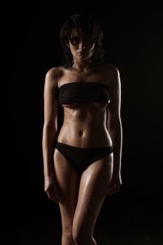 Artistic portrait of a woman in a bikini with dramatic lighting and dark background.