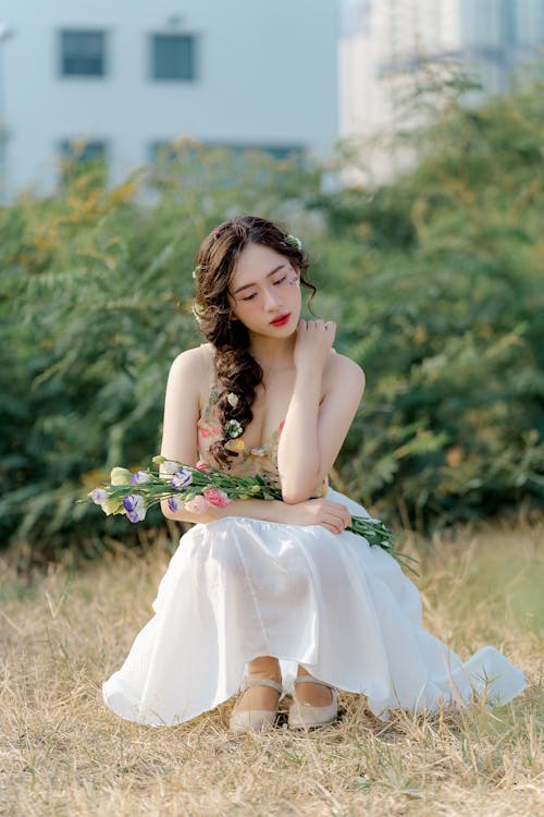 A woman in a white dress sitting on the ground