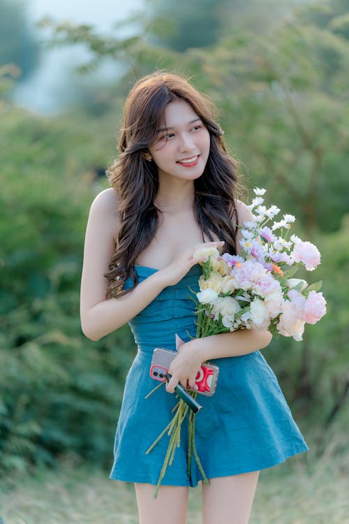 Brunette Woman in Blue Dress Holding Bouquet of Flowers 