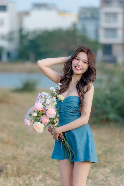 A beautiful young woman in a blue dress holding flowers