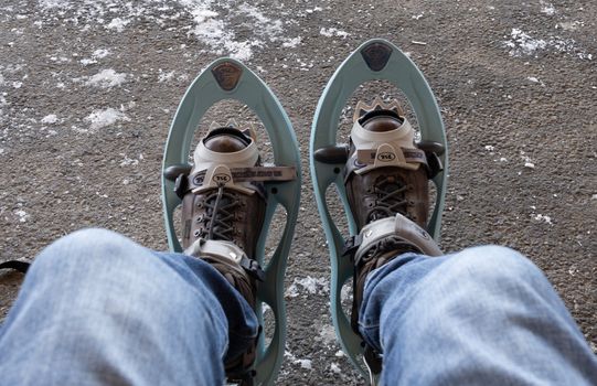 Feet in snowshoes and jeans resting, winter adventure perspective.