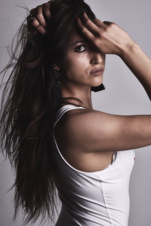 A woman with long hair and a white tank top