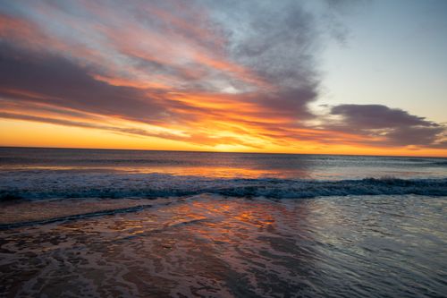 Free Captivating sunset over the ocean at a Cape Cod beach with vibrant colors reflecting on the waves. Stock Photo